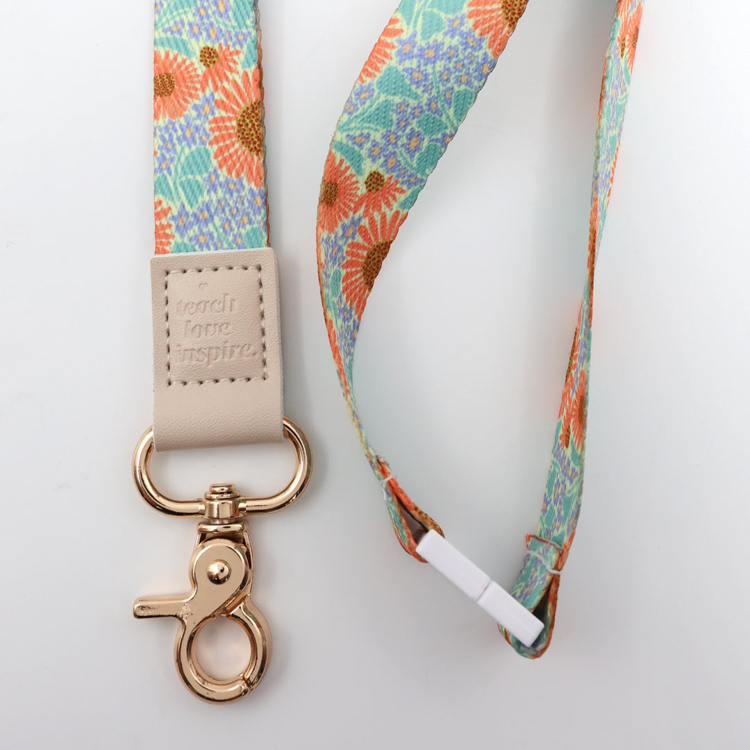 Floral patterned lanyard with a beige strap and gold clasp on a light gray background