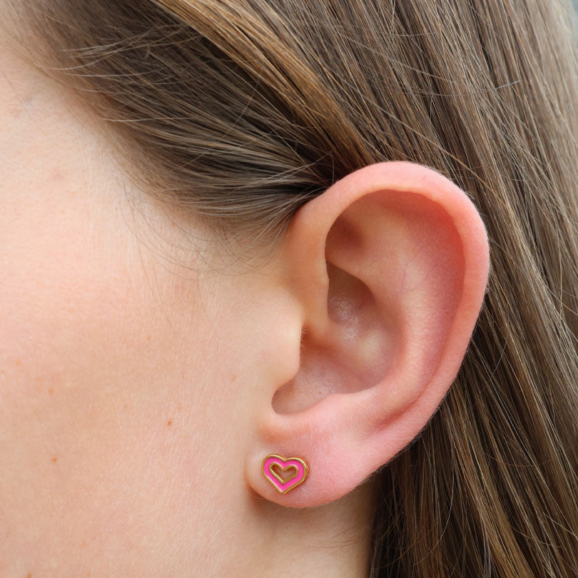 Close-up of an ear wearing a pink heart-shaped earring.