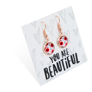 Rose gold earrings with floral design on a card that says 'You are Beautiful'.