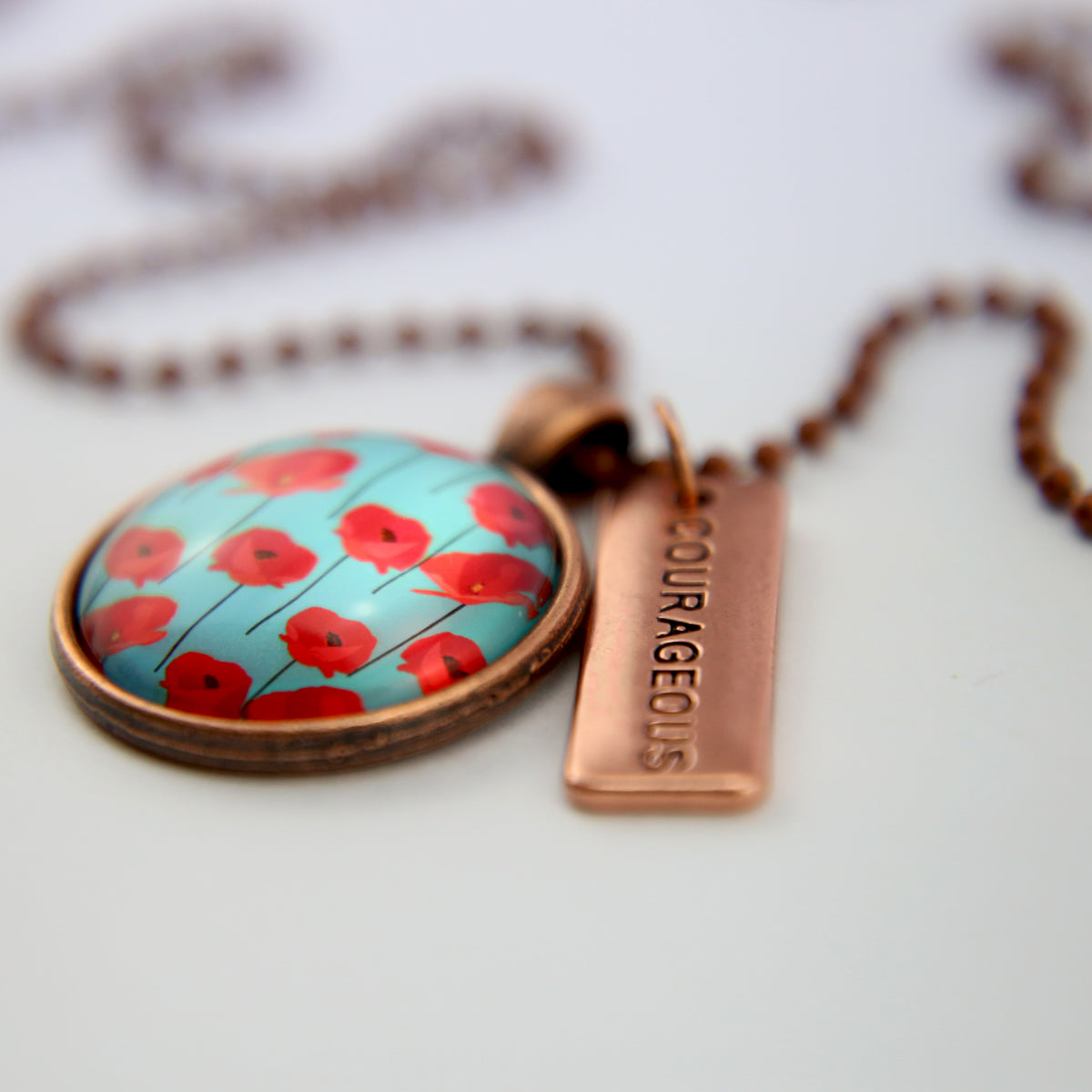 Necklace with floral pendant and 'COURAGEOUS' tag on a light background