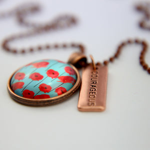 Necklace with floral pendant and 'COURAGEOUS' tag on a light background