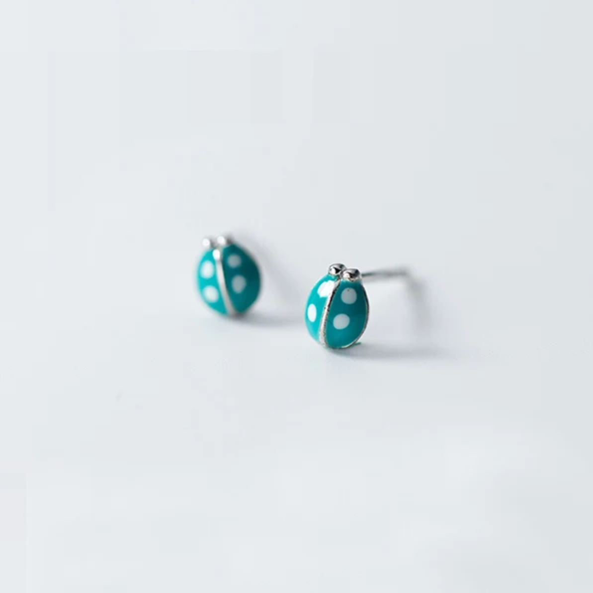 Tiny sterling silver earring studs in lady beetle shape with teal coloured enamel. Novelty shaped earrings.