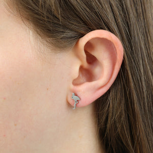 Close-up of an ear wearing a flamingo shaped earring 