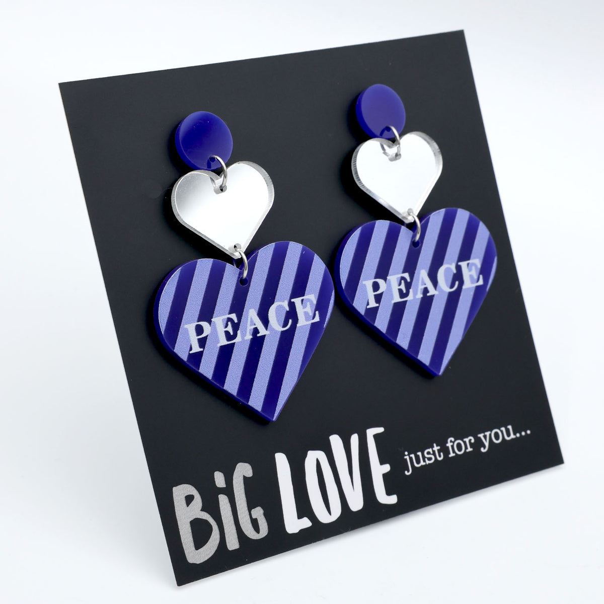 Heart-shaped earrings with 'PEACE' text on a 'BIG LOVE' card