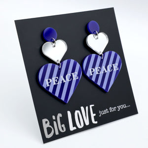 Heart-shaped earrings with 'PEACE' text on a 'BIG LOVE' card