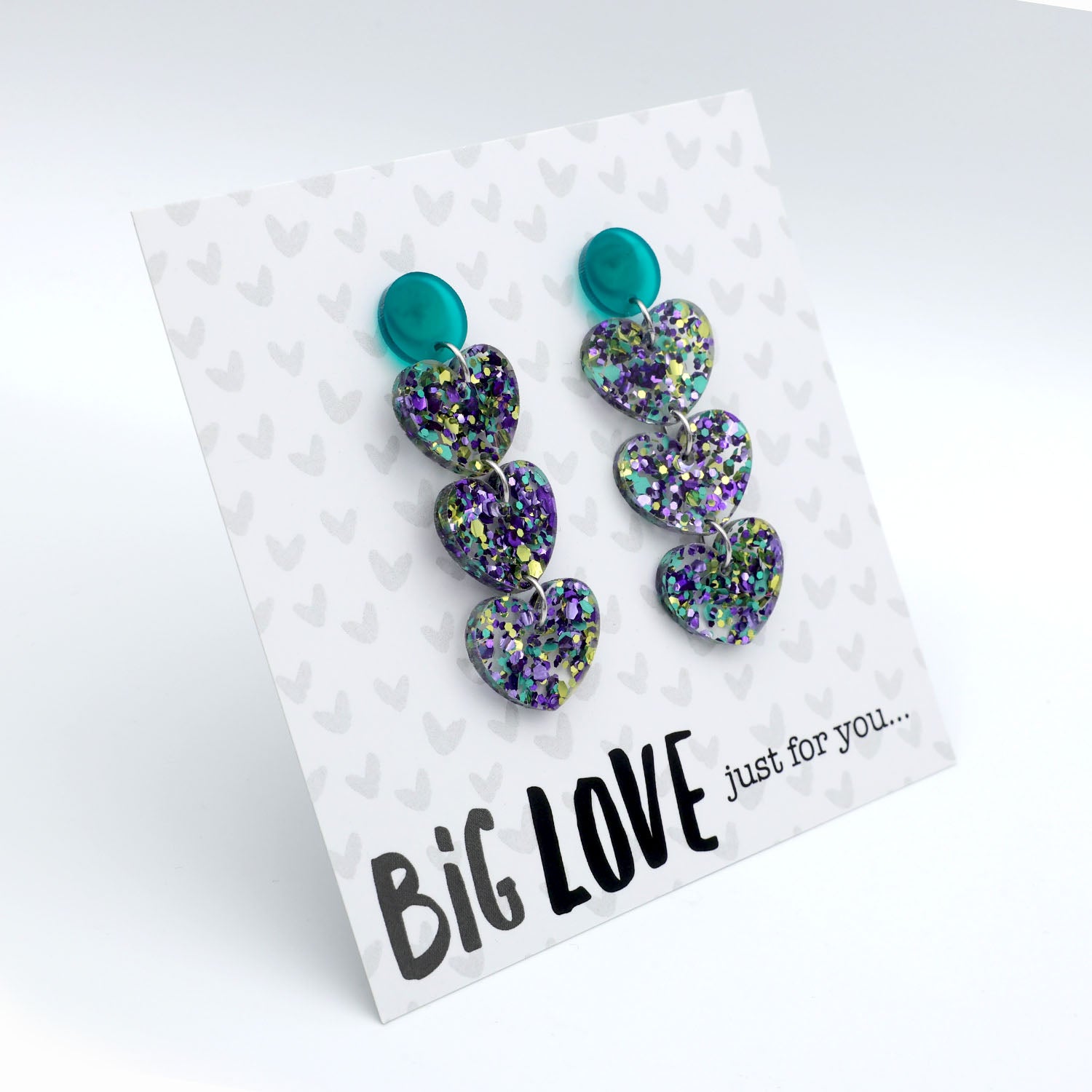 Pair of heart-shaped earrings with glittery finish on a card with 'Big Love just for you' text.
