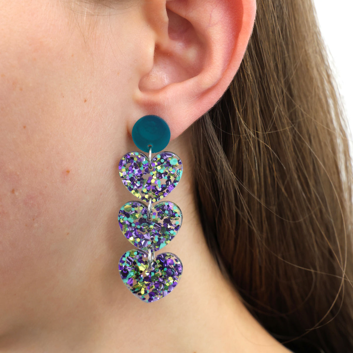 Close-up of a person wearing a colorful heart-shaped earring.
