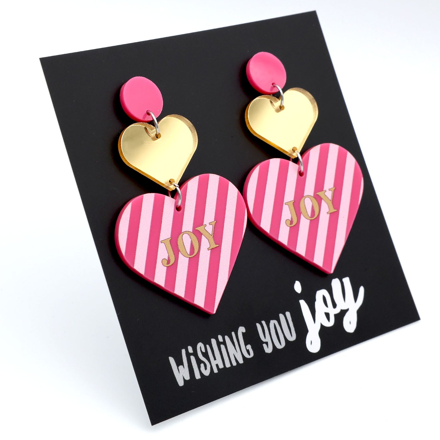 Heart-shaped earrings with pink and gold design on a black card with 'Wishing You Joy' text.