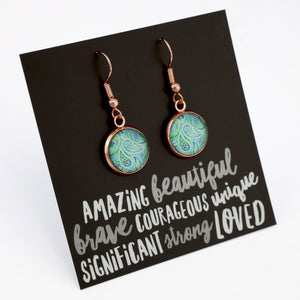 Teal paisley print rose gold dangle earrings on amazing inspiring word card on white background.