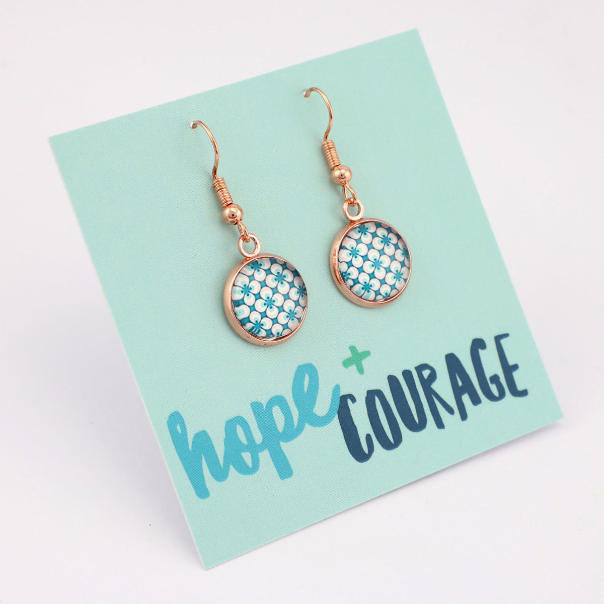 Teal print silver dangle earrings on hope and courage inspiring word card on white background.