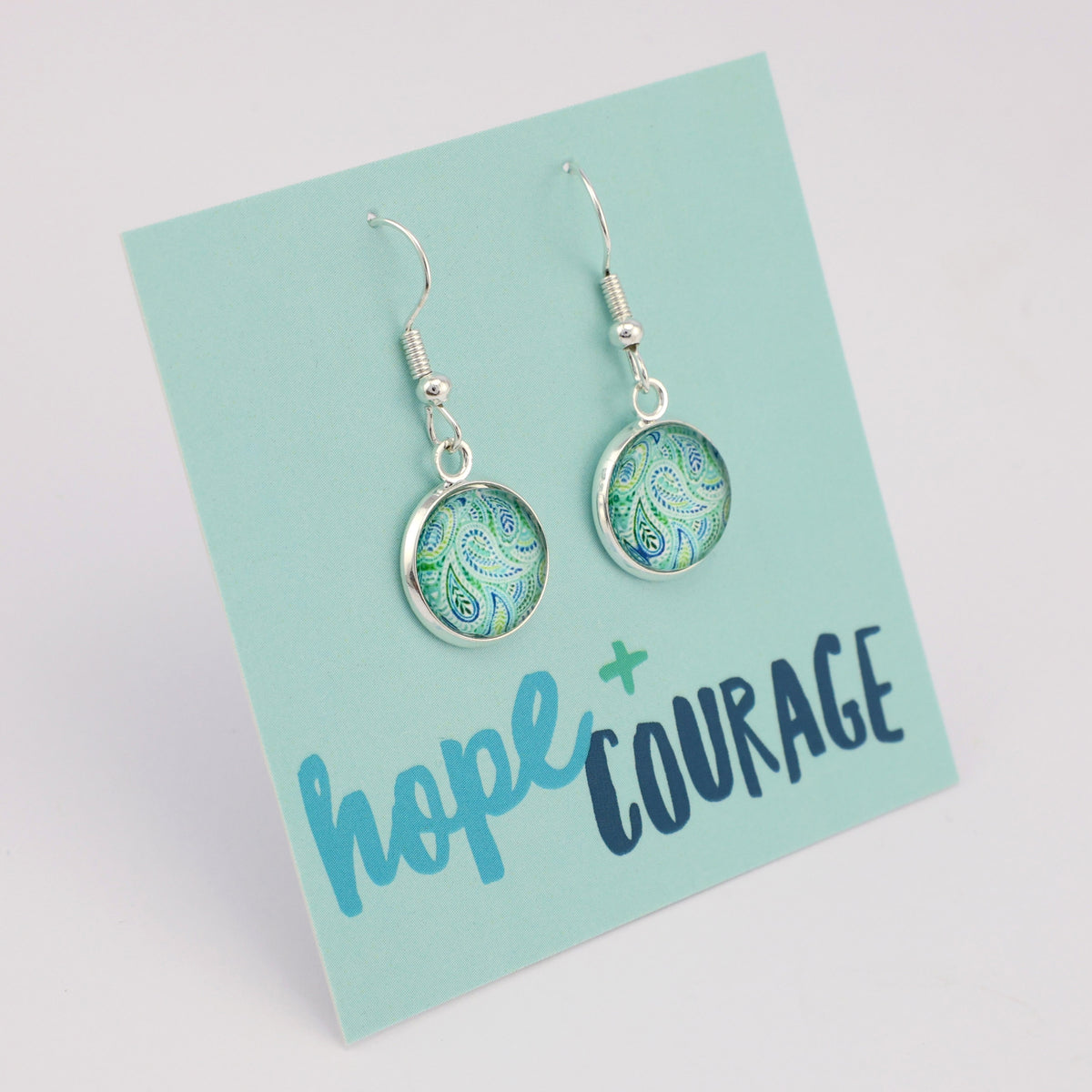 Teal print silver dangle earrings on hope and courage inspiring word card on white background.