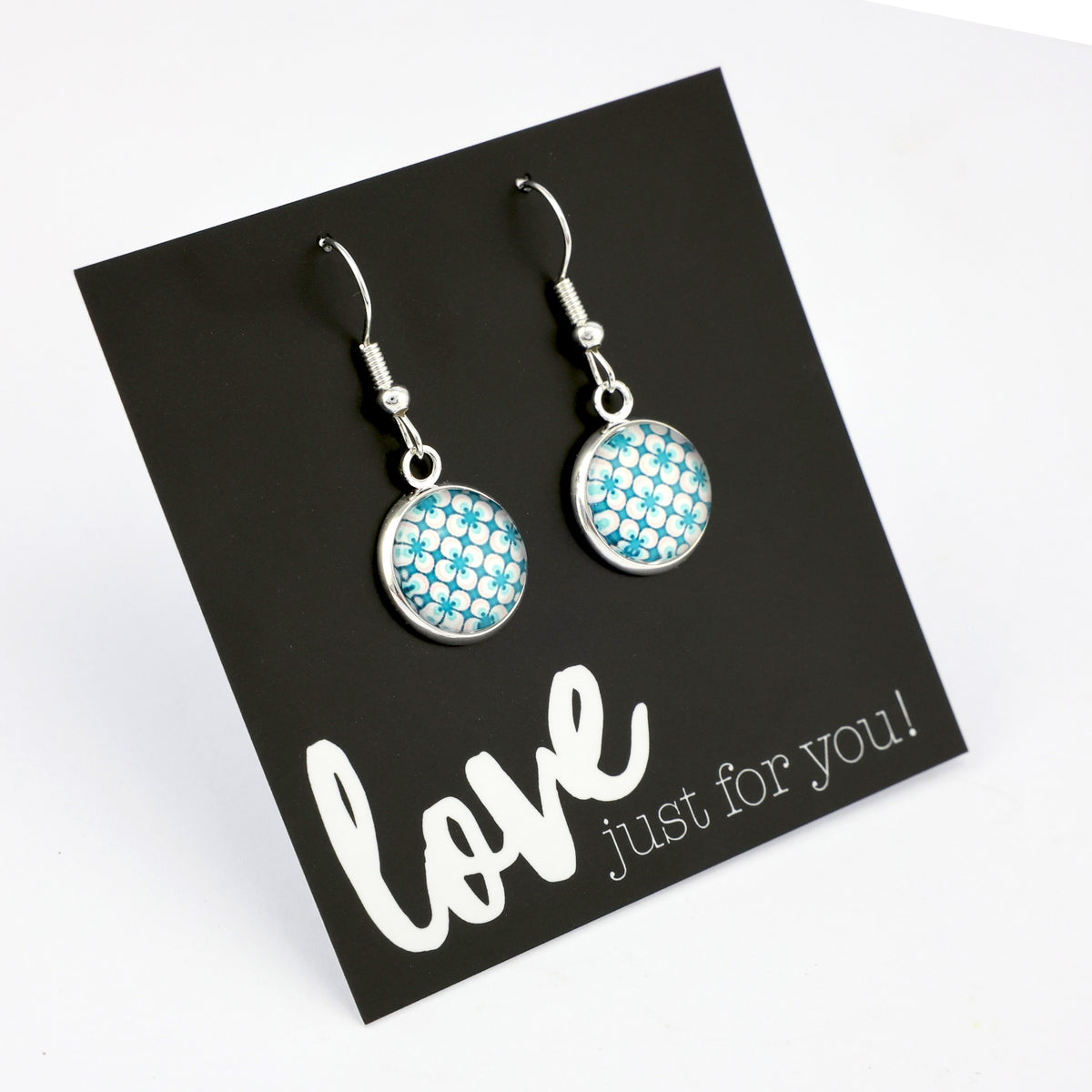 Teal print silver dangle earrings on love and inspiring word card on white background.