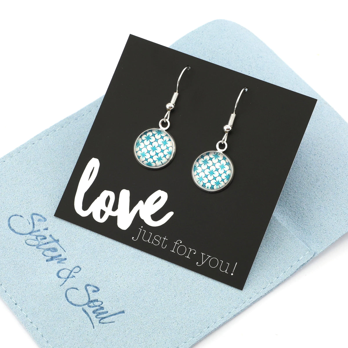 Teal print silver dangle earrings on love and inspiring word card on white background.