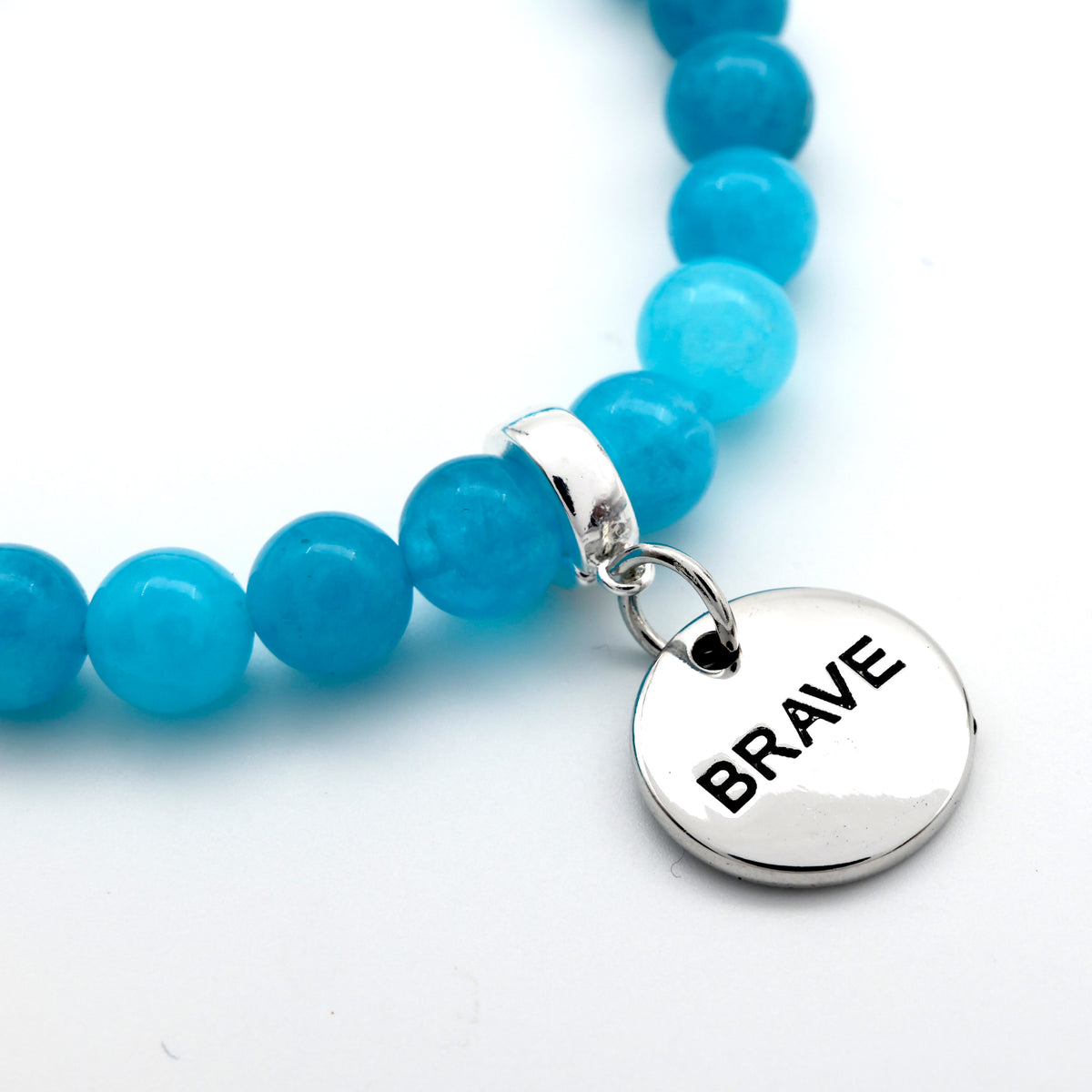 Blue beaded bracelet with a silver 'BRAVE' charm on a white background