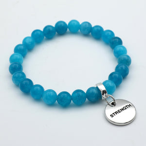 Blue beaded bracelet with a 'STRENGTH' charm on a light gray background