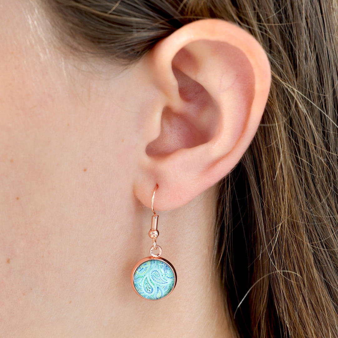 Close-up of an ear wearing a turquoise earring with rose gold frame