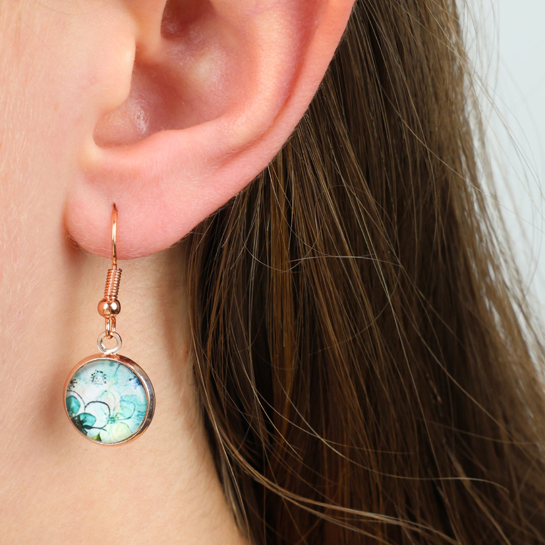 Close-up of an ear wearing a round earring with a colorful design.