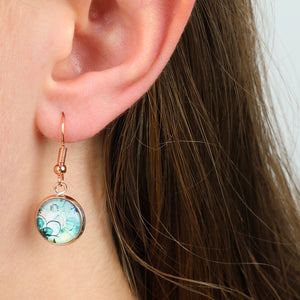 Close-up of an ear wearing a round earring with a colorful design.
