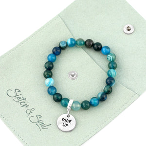 Beaded bracelet with 'Rise Up' charm on a green card with 'Sister & Soul' branding.