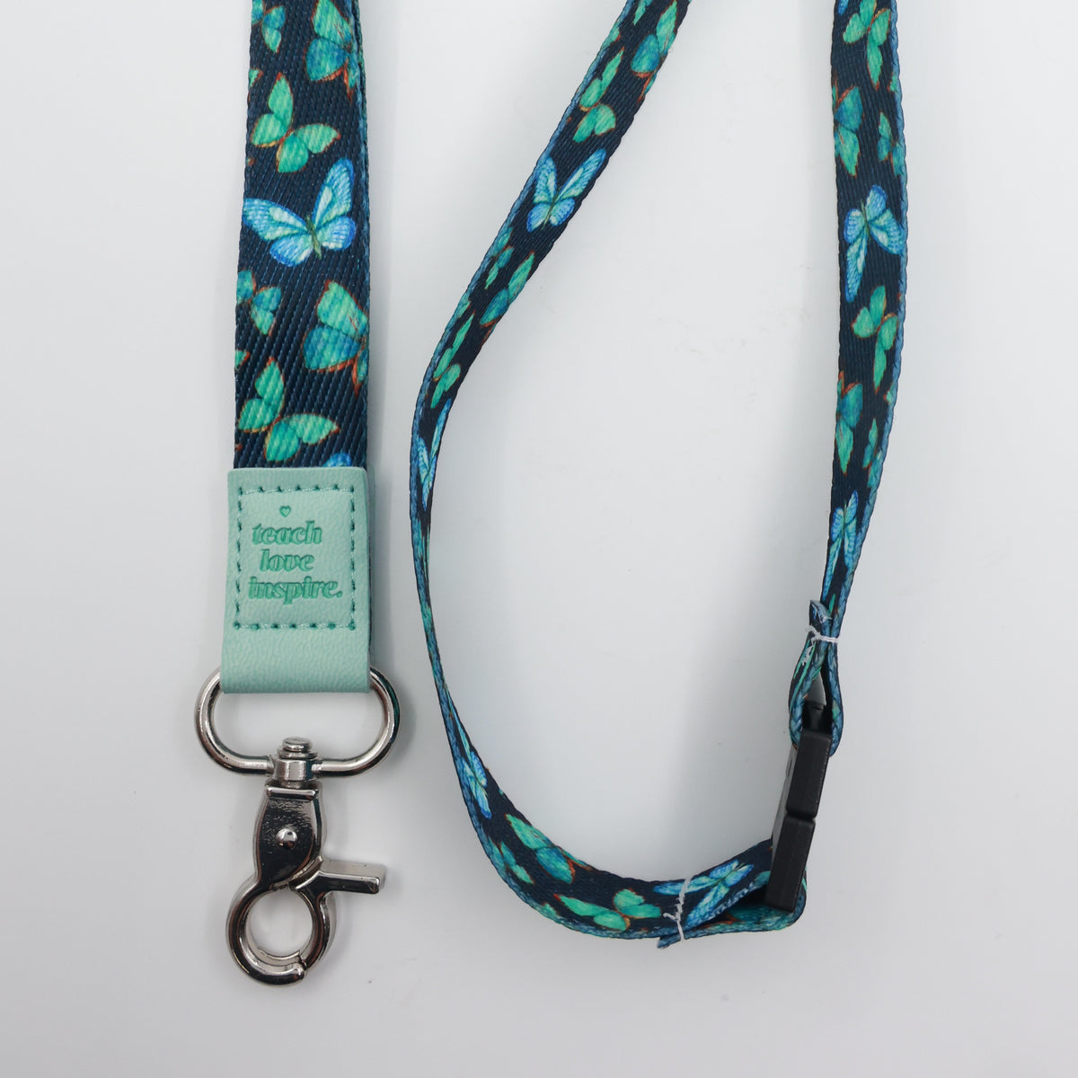 Teach Love Inspire embossed on a navy lanyard with teal butterflies and mint trim and a lobster clasp.