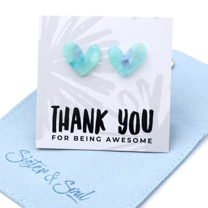 Heart-shaped light blue and green iridescent stud earrings displayed on a white card that reads 'THANK YOU FOR BEING AWESOME,' resting on a light blue fabric pouch with 'Soul & Soul' written in blue script.