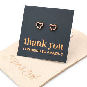 Rose gold heart-shaped earrings on a 'thank you' card with personalized message.