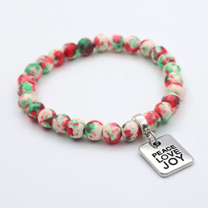 Beaded bracelet with 'Peace Love Joy' charm on a white background