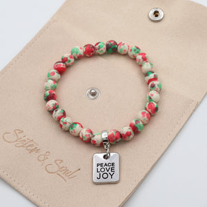 Beaded bracelet with 'Peace Love Joy' charm on a beige card