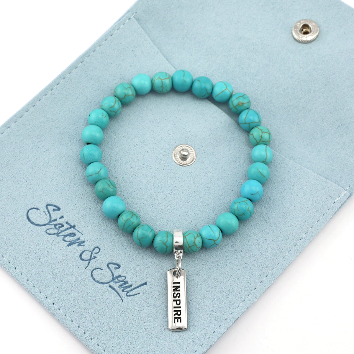 Turquoise beaded bracelet with 'INSPIRE' charm on a light blue card