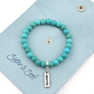 Turquoise beaded bracelet with 'INSPIRE' charm on a light blue card