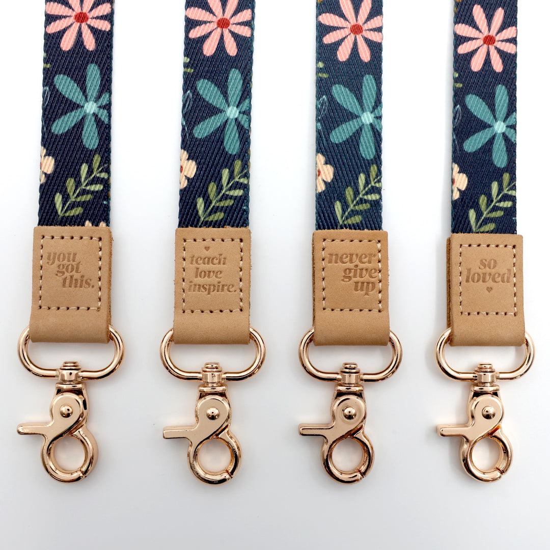 Four floral lanyards with motivational phrases and gold hooks on a white background