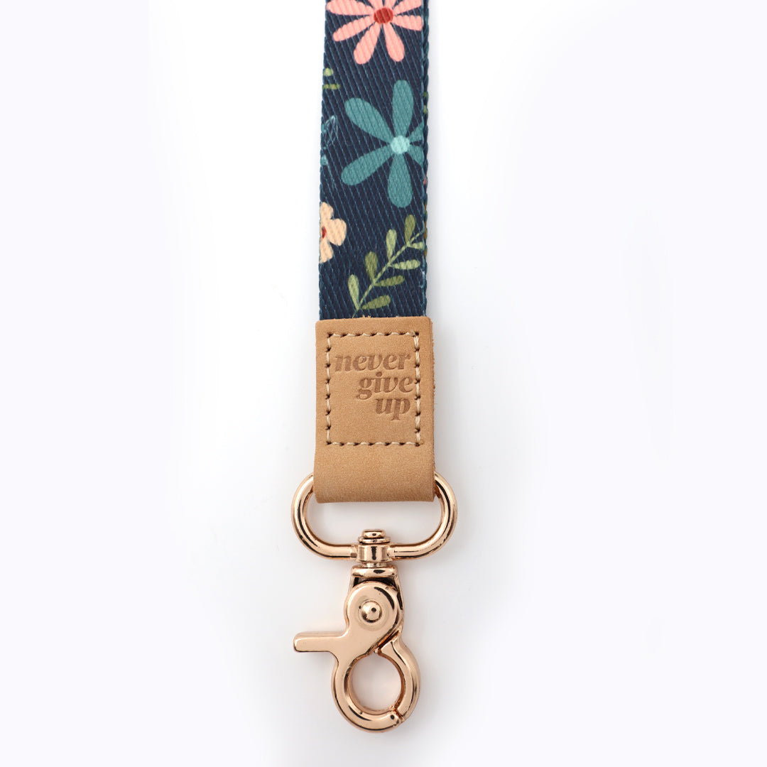 Floral patterned keychain with 'never give up' tag on a white background