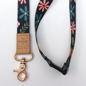 Floral patterned lanyard with a brown leather tag and gold clasp on a white background