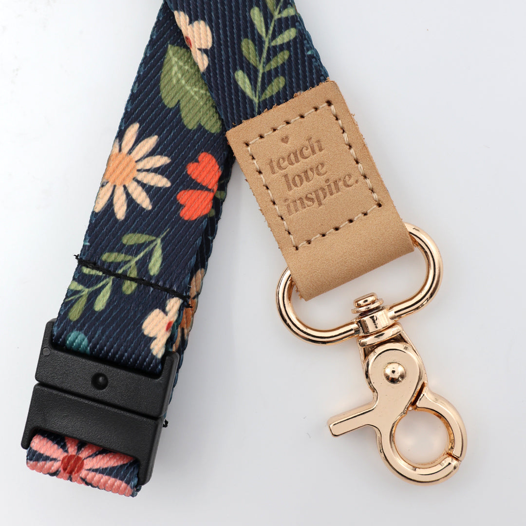 Floral patterned lanyard with a gold clasp and 'teach love inspire' tag on a white background