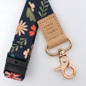 Floral patterned lanyard with a gold clasp and 'teach love inspire' tag on a white background