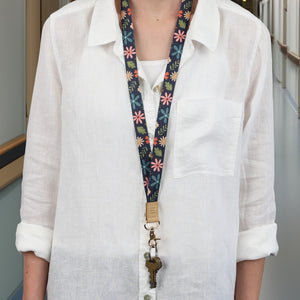 Person wearing a white shirt with a colorful floral lanyard around their neck.