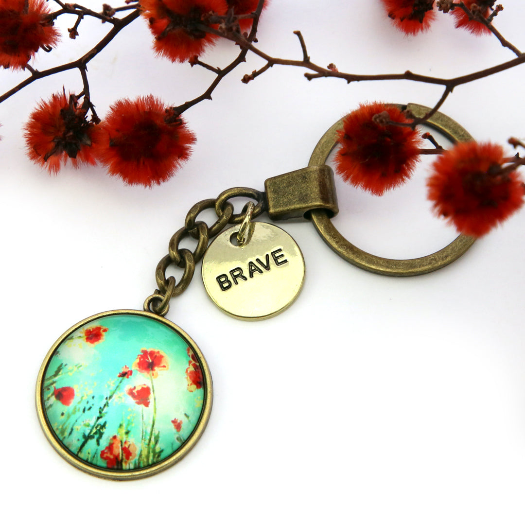 Keychain with floral design and 'BRAVE' tag on a white background