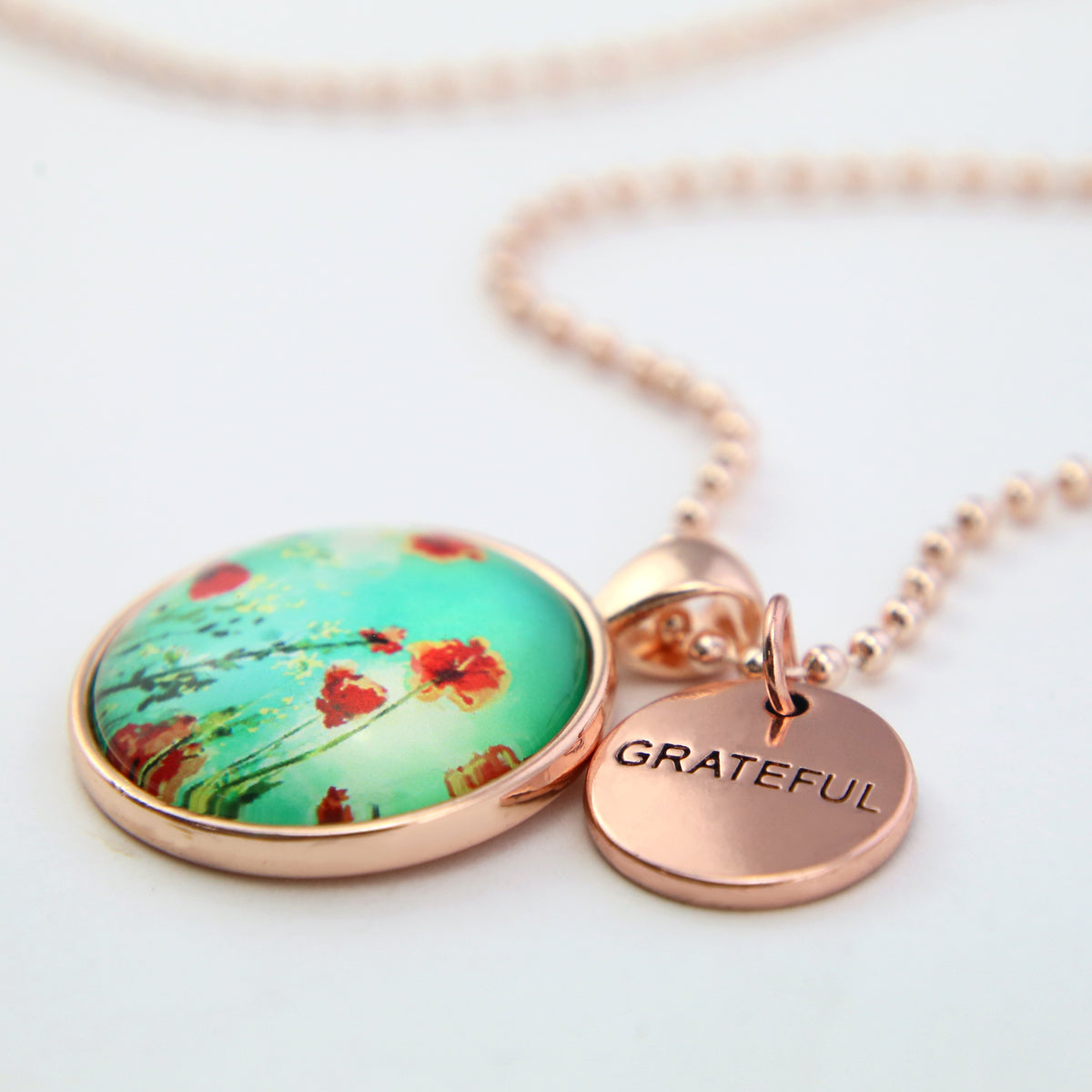 Necklace with floral pendant and 'GRATEFUL' charm on a light background