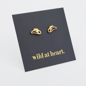 Gold cowgirl hat earrings on a black card with 'wild at heart.' text