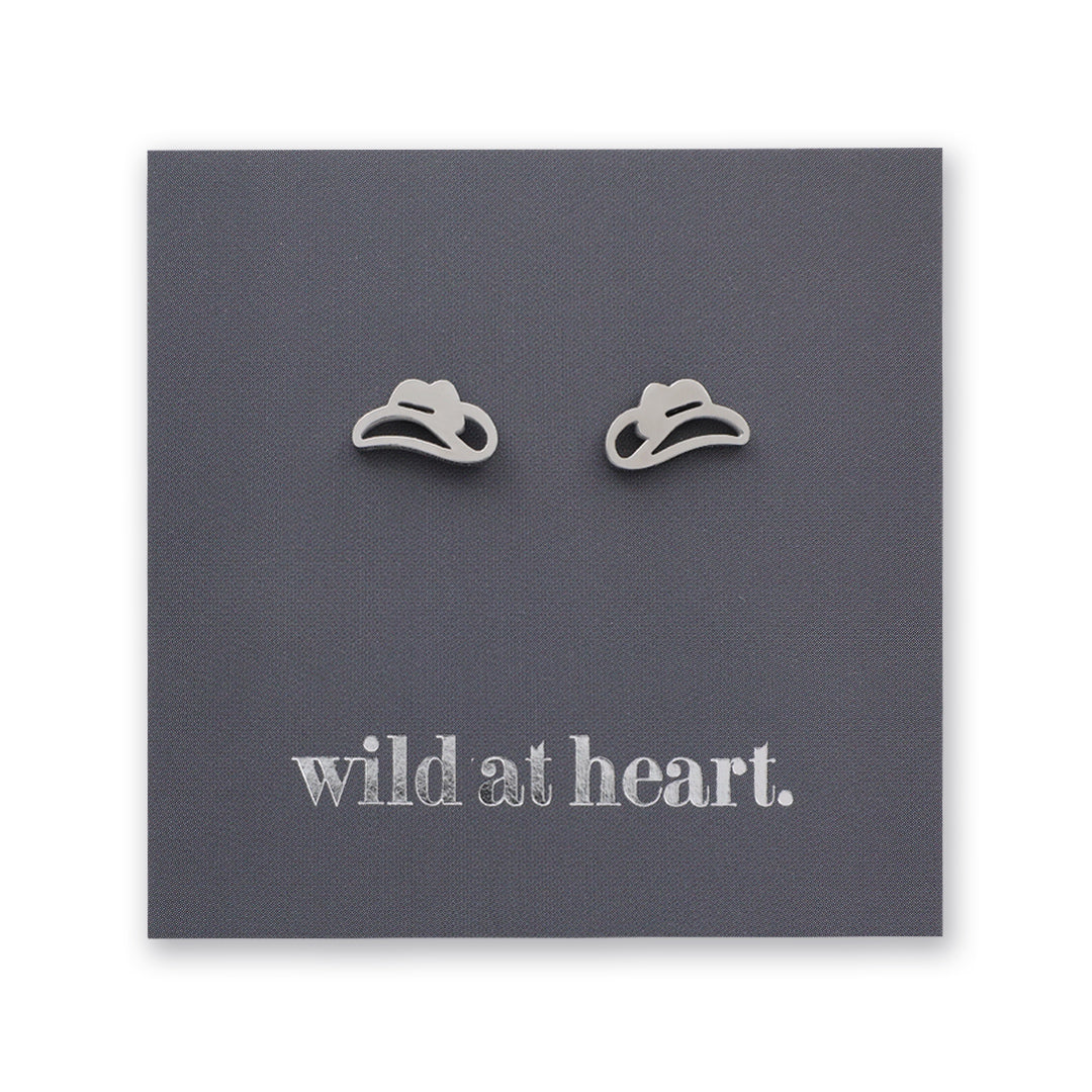Silver cowgirl hat earrings on a black card with 'wild at heart.' text.