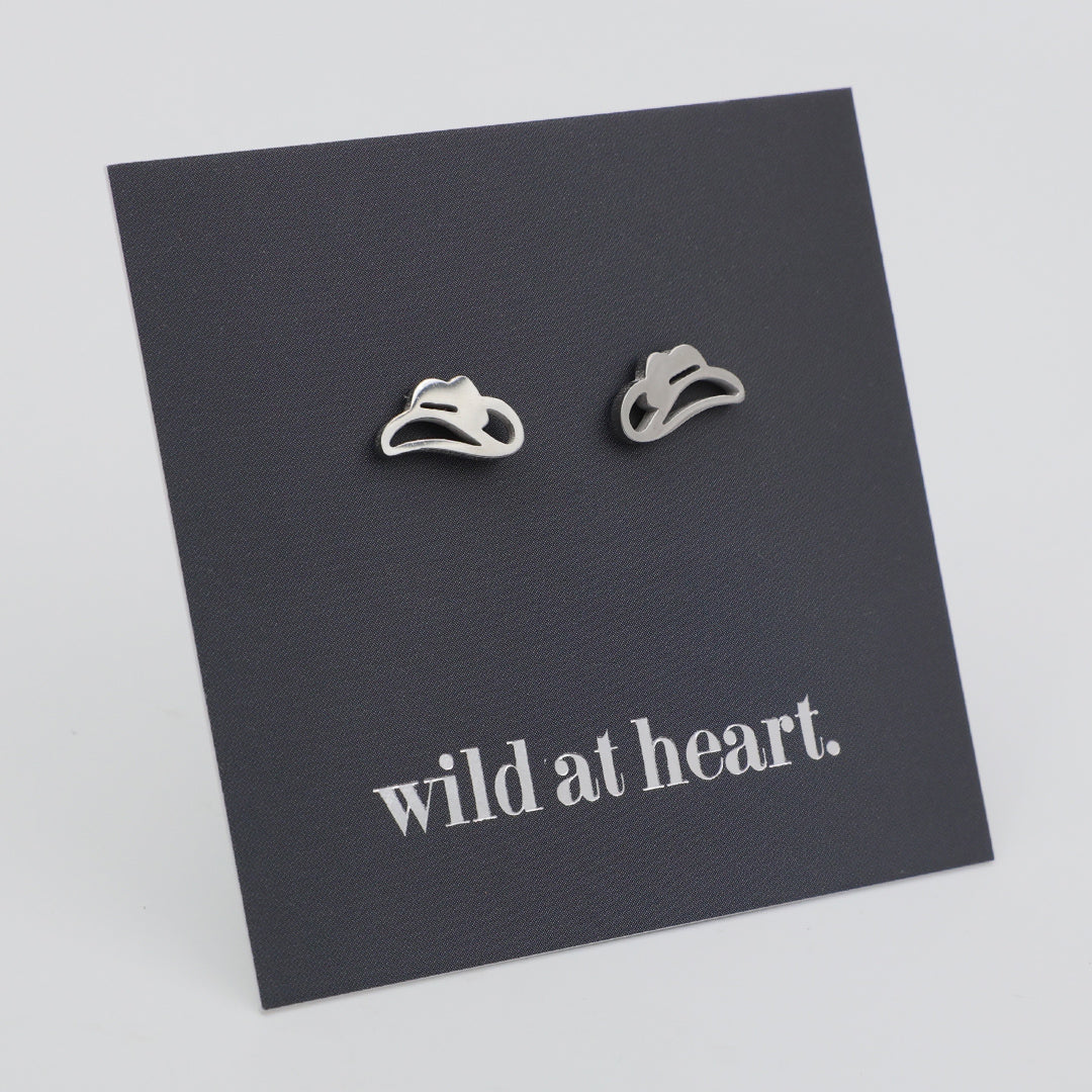 Silver cowgirl hat earrings on a black card with 'wild at heart.' text