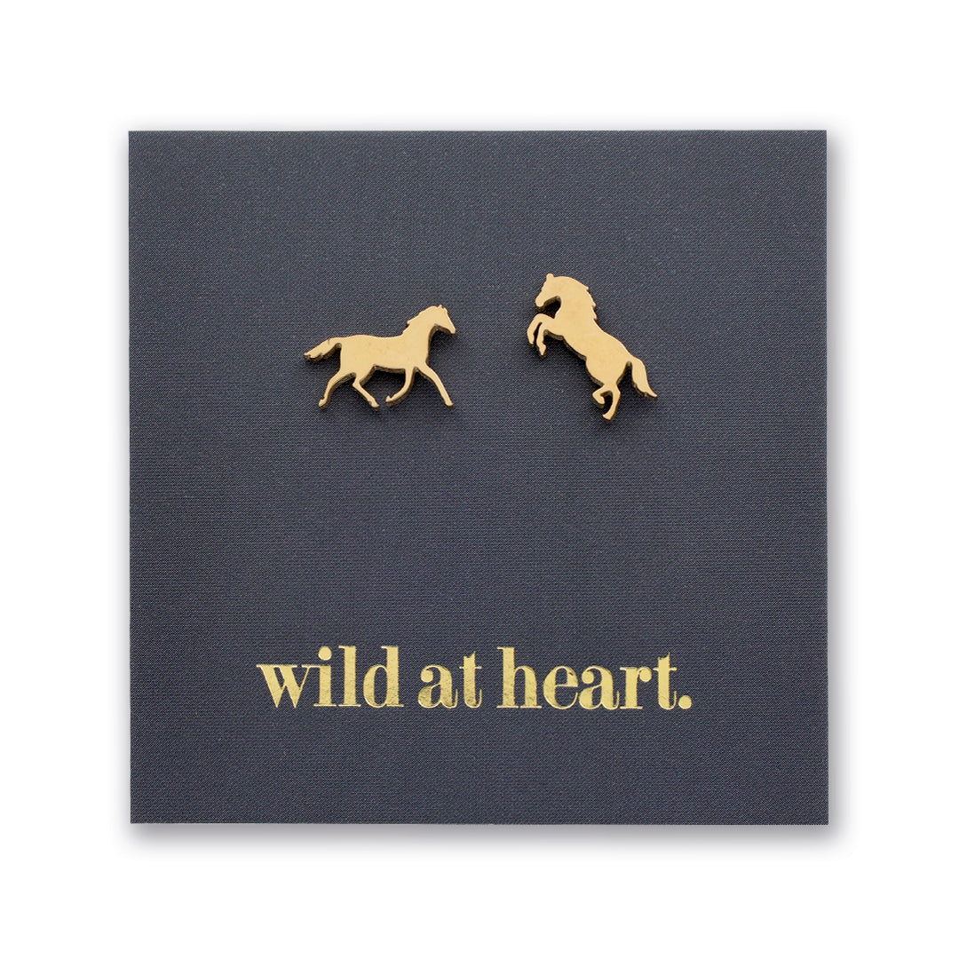 Gold horse earrings on a black card with 'wild at heart.' text