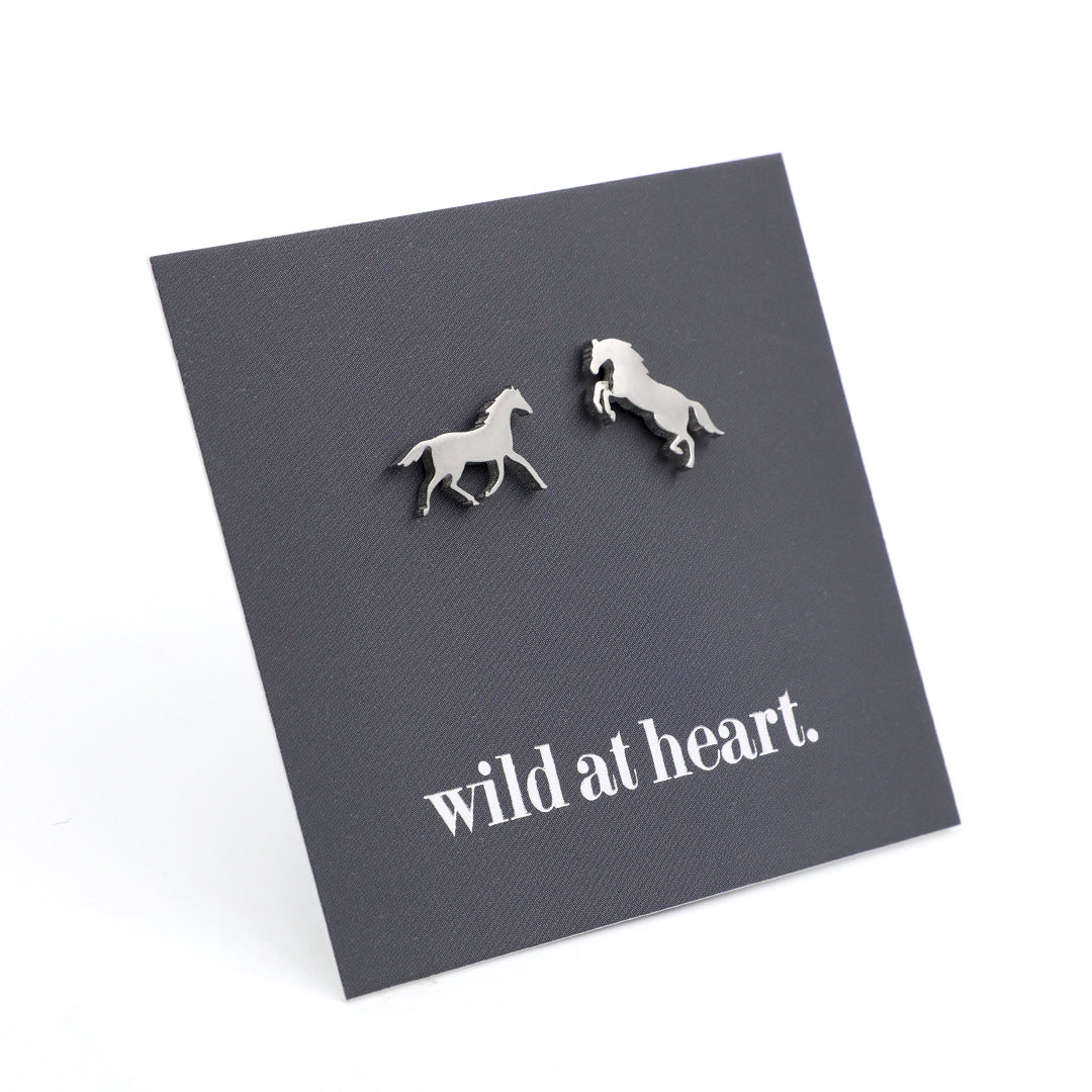 Silver horse earrings on a black card with 'wild at heart.' text 