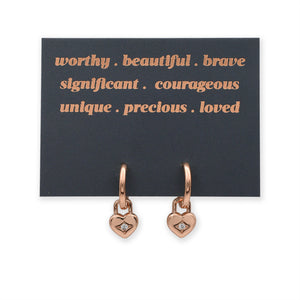 Rose gold heart-shaped earrings on a card with positive affirmations.