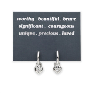 Silver heart-shaped earrings on a card with motivational phrases