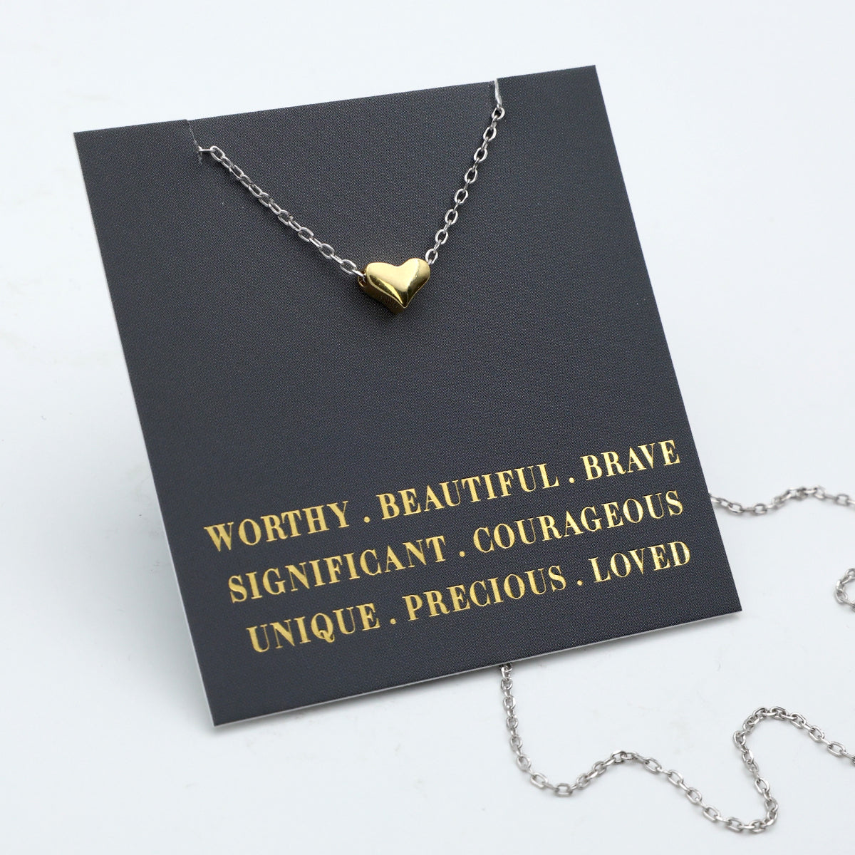 Necklace with a heart pendant on a black card with gold text