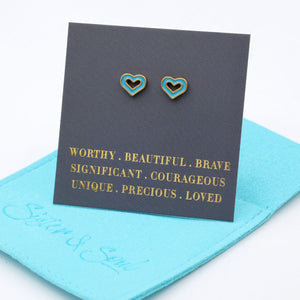 Heart-shaped earrings on a card with motivational phrases, placed on a blue cloth.