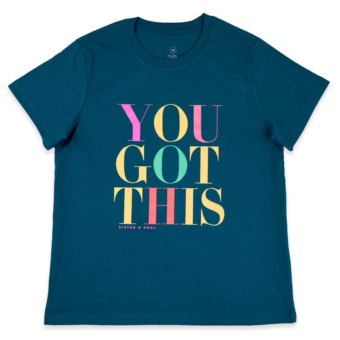 A dark teal blue short-sleeve t-shirt with a colorful graphic text print reading 'YOU GOT THIS' in pink, yellow, and mint green, with 'BISTER & SOUL.' printed in small text below.