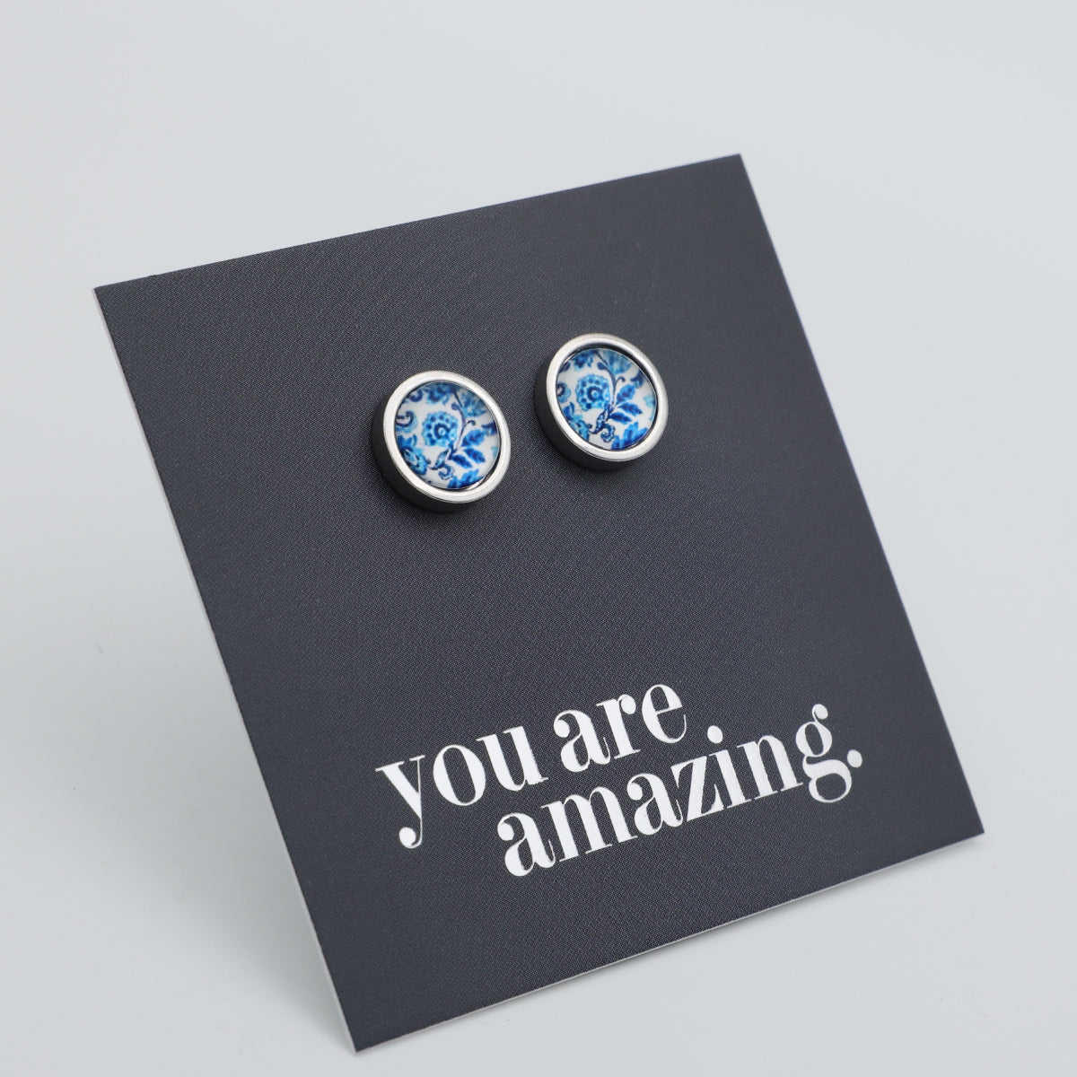 Pair of blue floral earrings on a black card with 'you are amazing' text