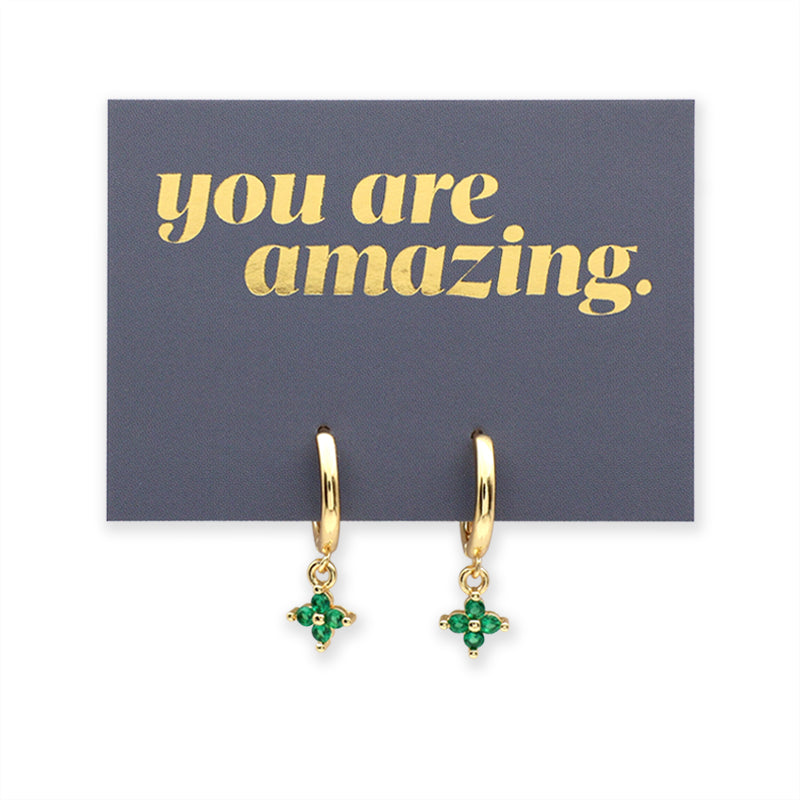 Gold hoop earrings with green gemstones on a card with 'you are amazing' text.